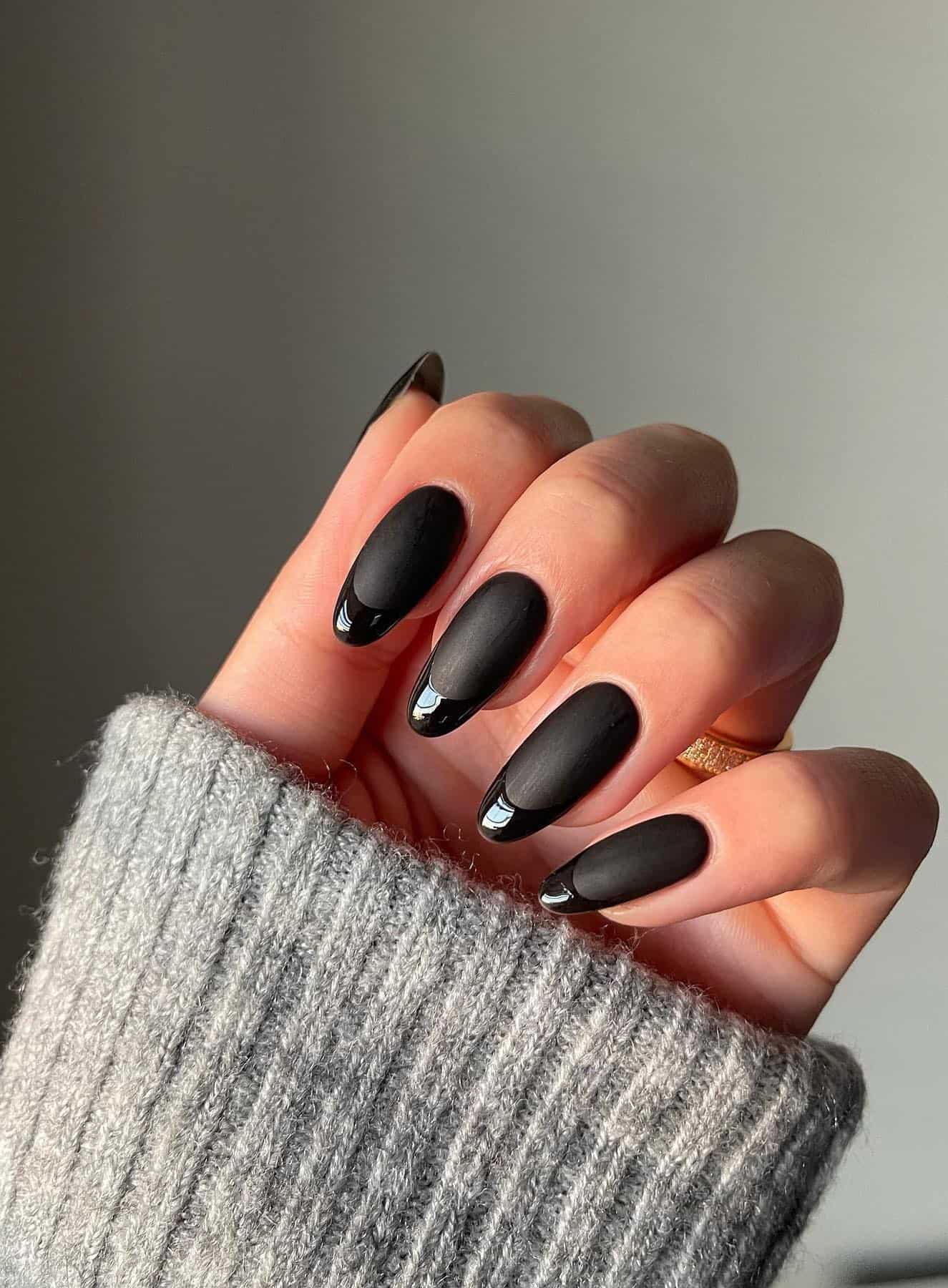 Almond nails in matte black with glossy black French tips.