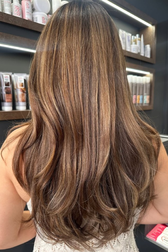 Long wavy hair with glossy toffee brown balayage highlights on a brunette base