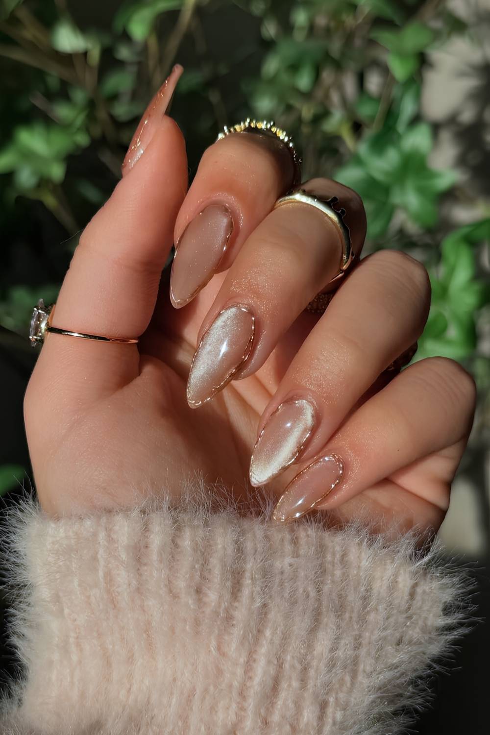 Almond nude nails with a golden cat-eye magnetic shimmer and thin gold chrome outline edges