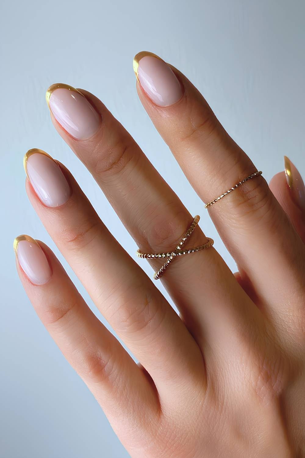 Milky nude almond nails with thin gold chrome french tips
