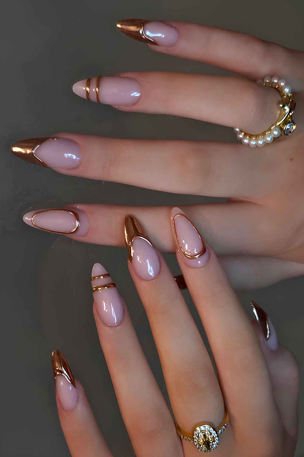Long almond nails with a nude pink base and gold chrome French tips with thin line-art outlines