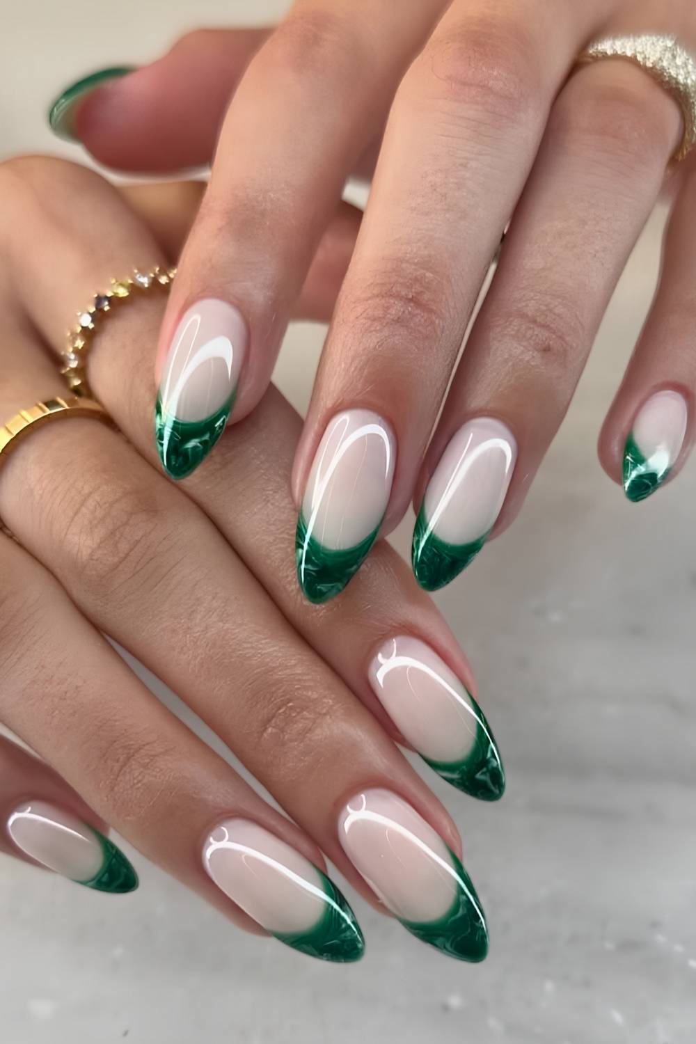 Medium almond nails with nude base and emerald marble French tips