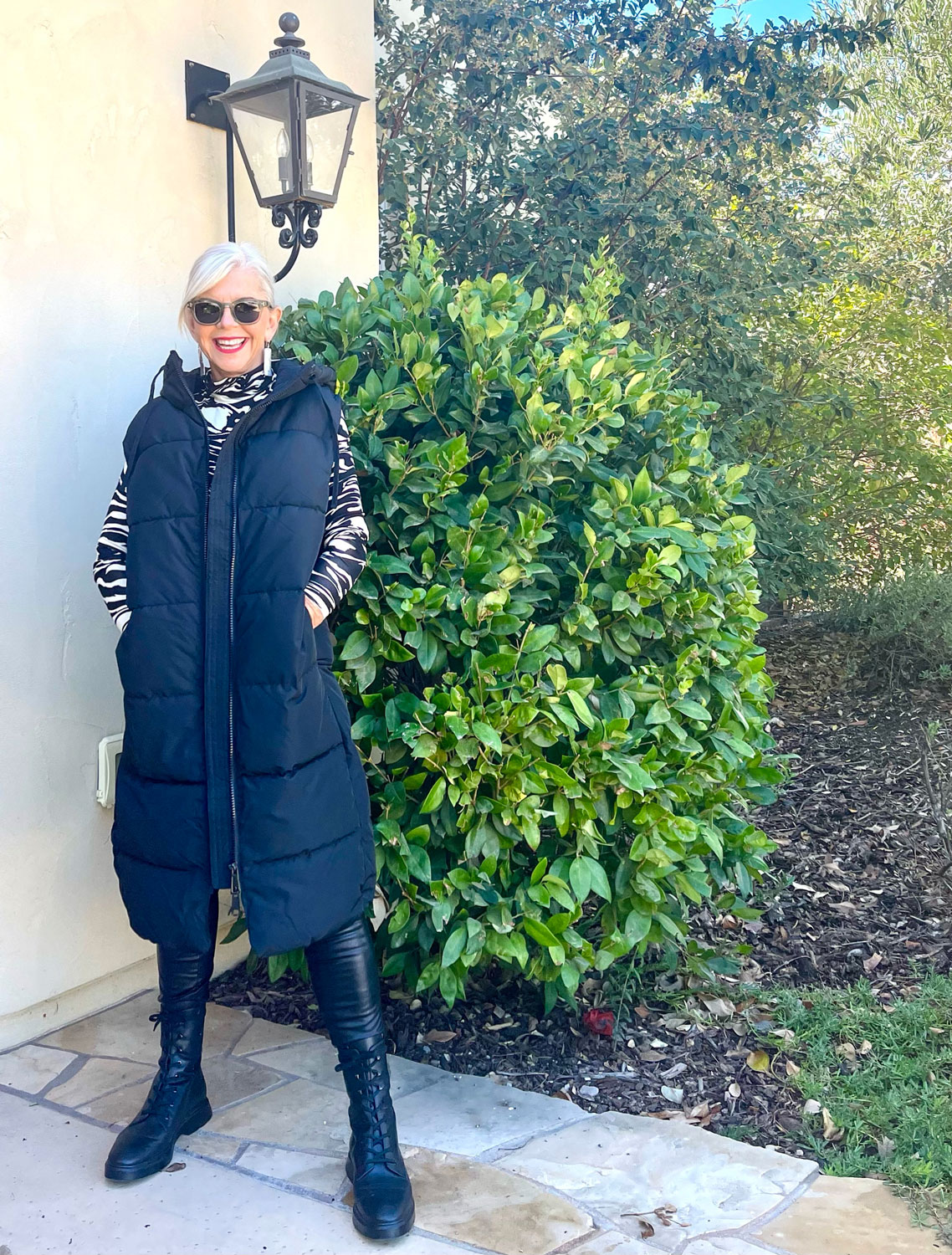 Senior woman in a burgundy quilted vest over a gray turtleneck with black pants
