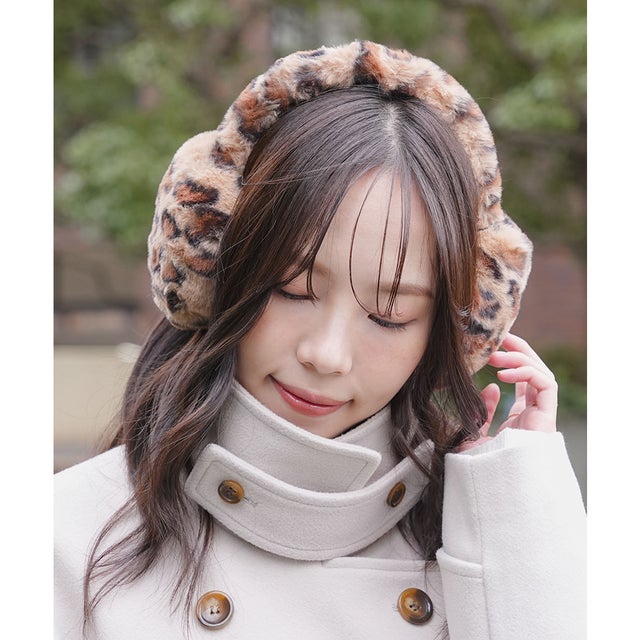 Woman wearing leopard print earmuffs and a cream high-collar coat