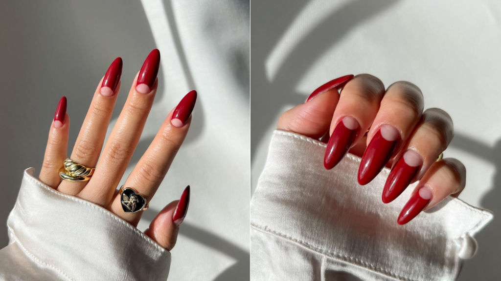 Cherry red nails with a nude half-moon left bare at the cuticle