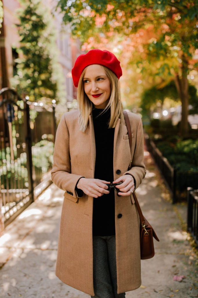 Woman wearing a red beret with a houndstooth coat and leggings