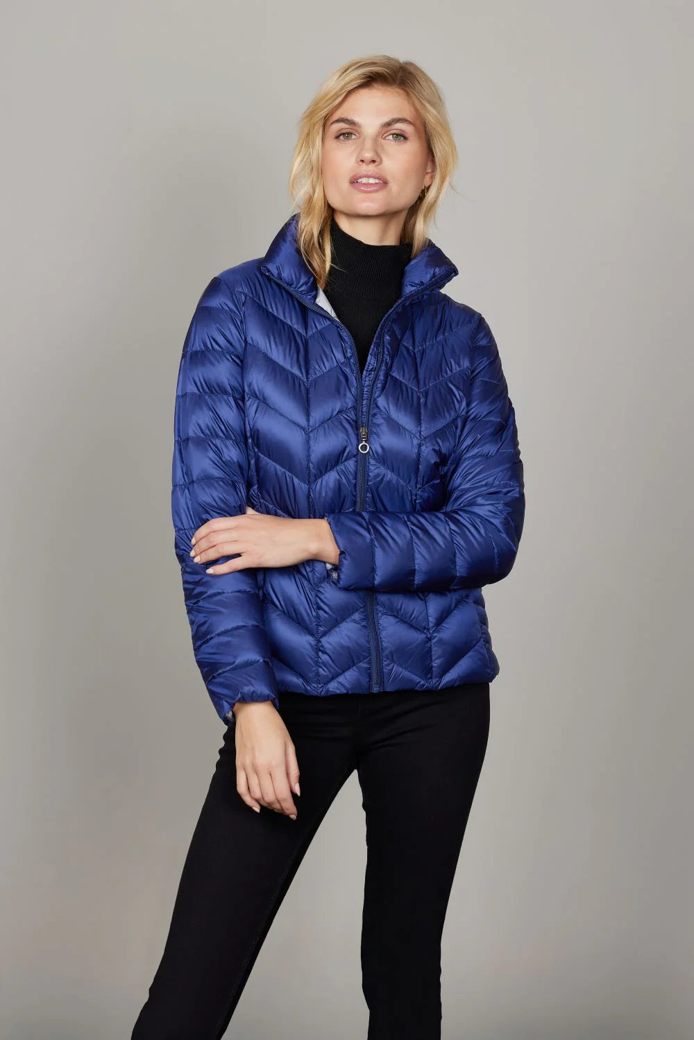 A woman wearing a cobalt blue long puffer coat with black layers
