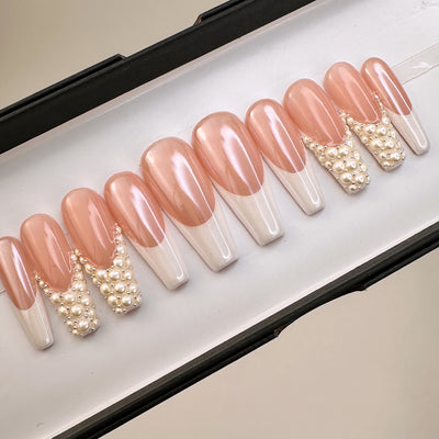Long coffin press-on nails in peachy nude with white french tips and pearl cluster accents