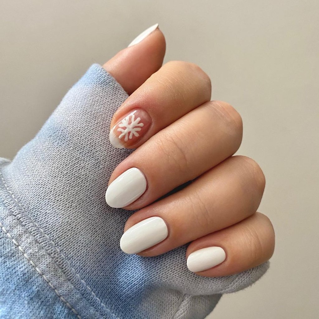 White oval nails with a white snowflake on a sheer pink accent nail
