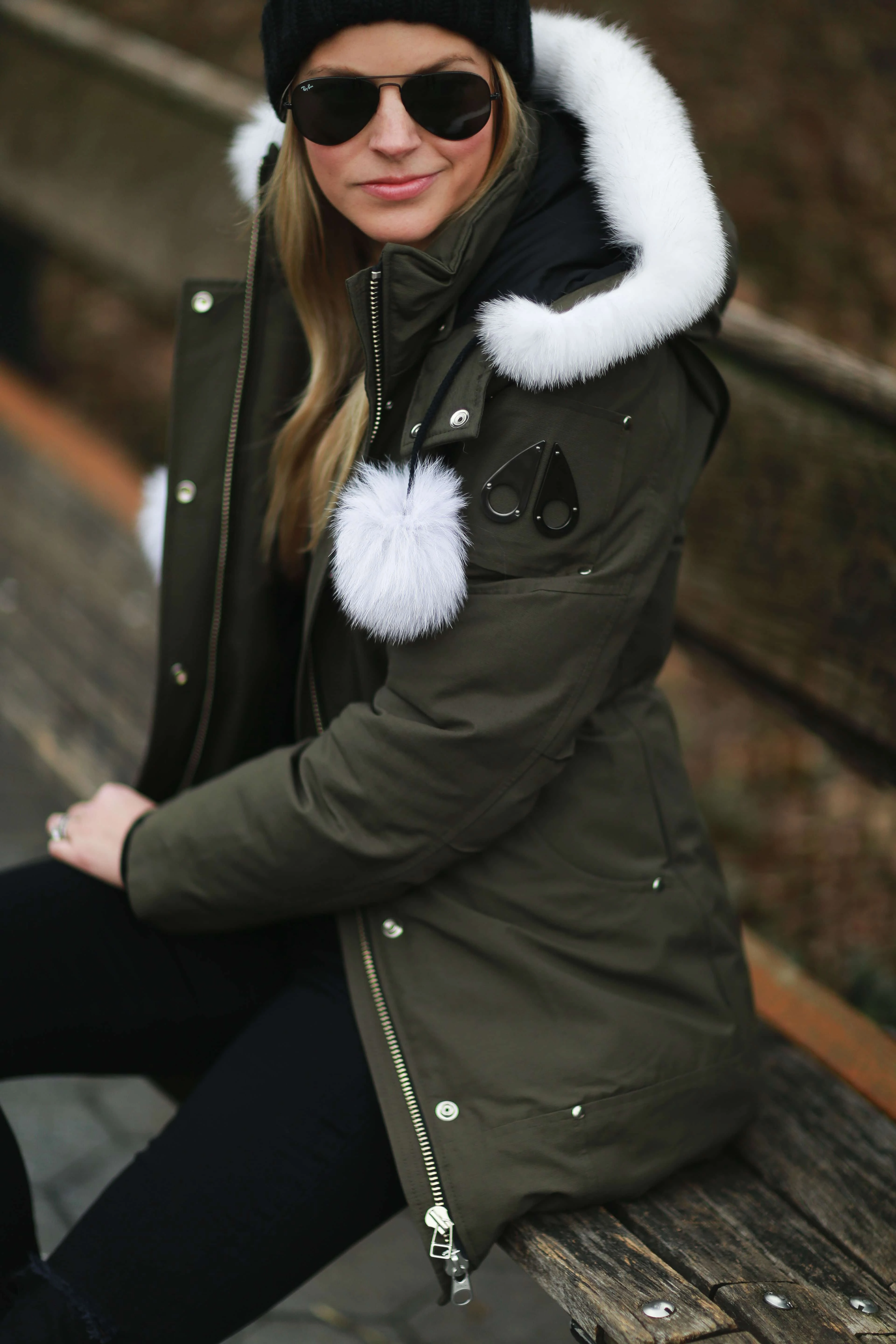 Close-up of an olive parka with a white fur-trimmed hood and black beanie