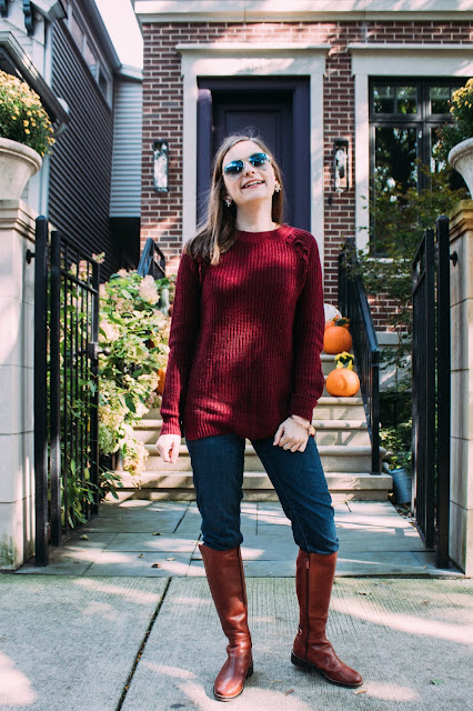 woman in burgundy chunky-knit sweater, dark skinny jeans and cognac riding boots