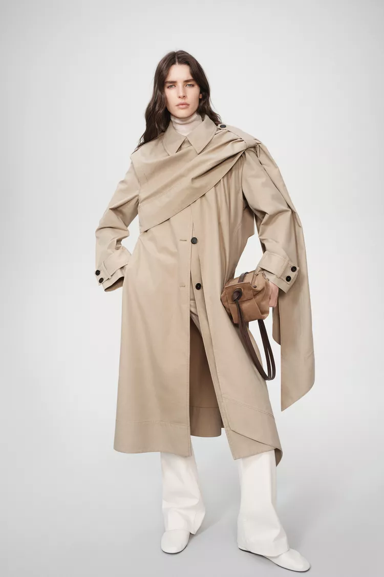 Classic trench coat layered over knit layers with a skirt for a chic winter outfit