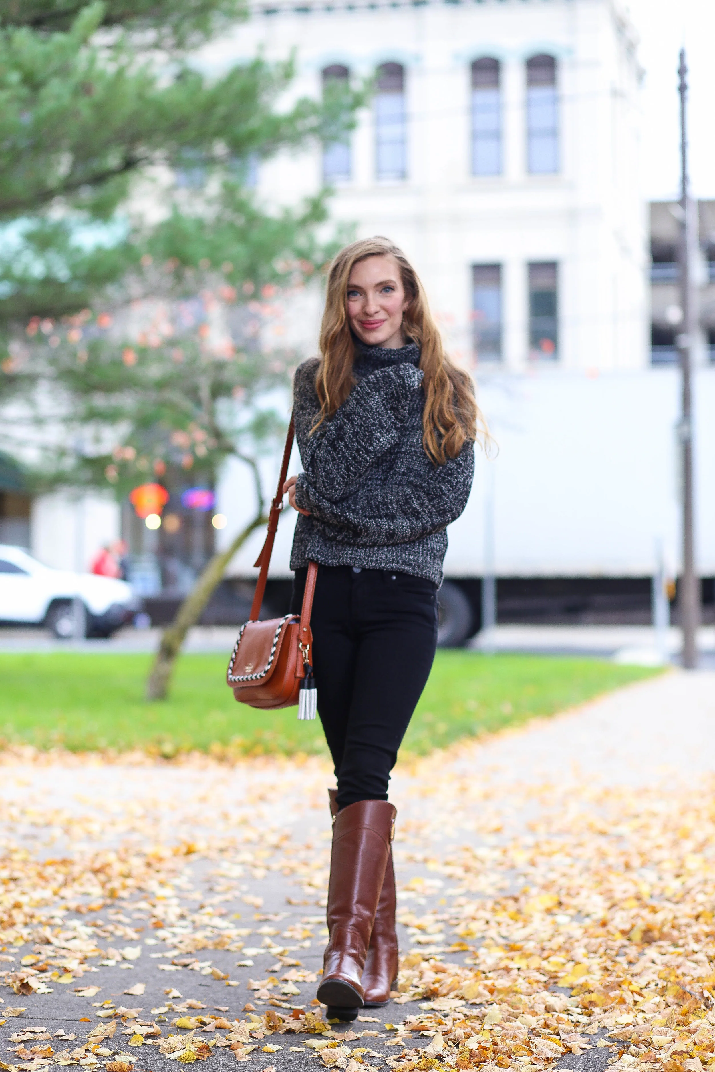 woman in charcoal cowl-neck sweater, black skinny jeans and cognac riding boots