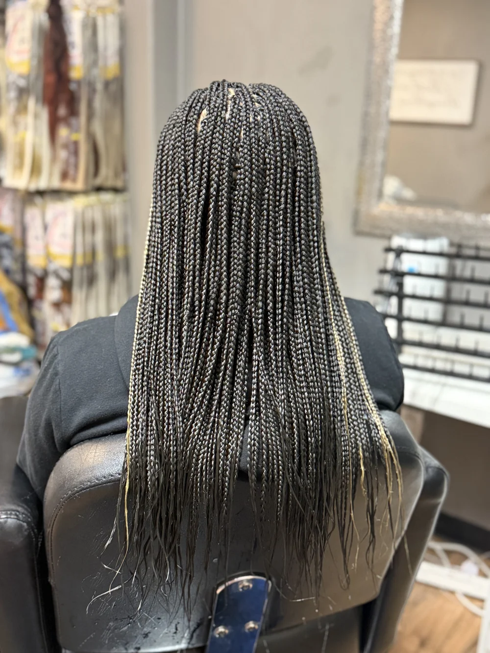 Back view of waist-length black box braids in a salon chair