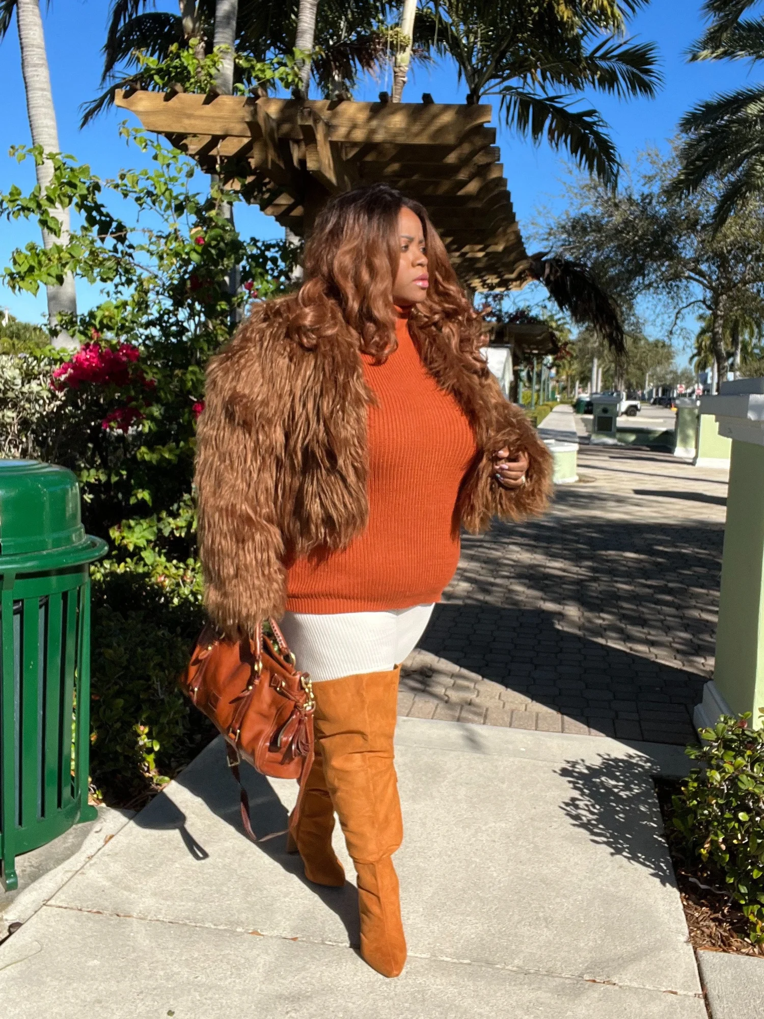 Woman in brown faux fur coat with rust knit co-ord and boots