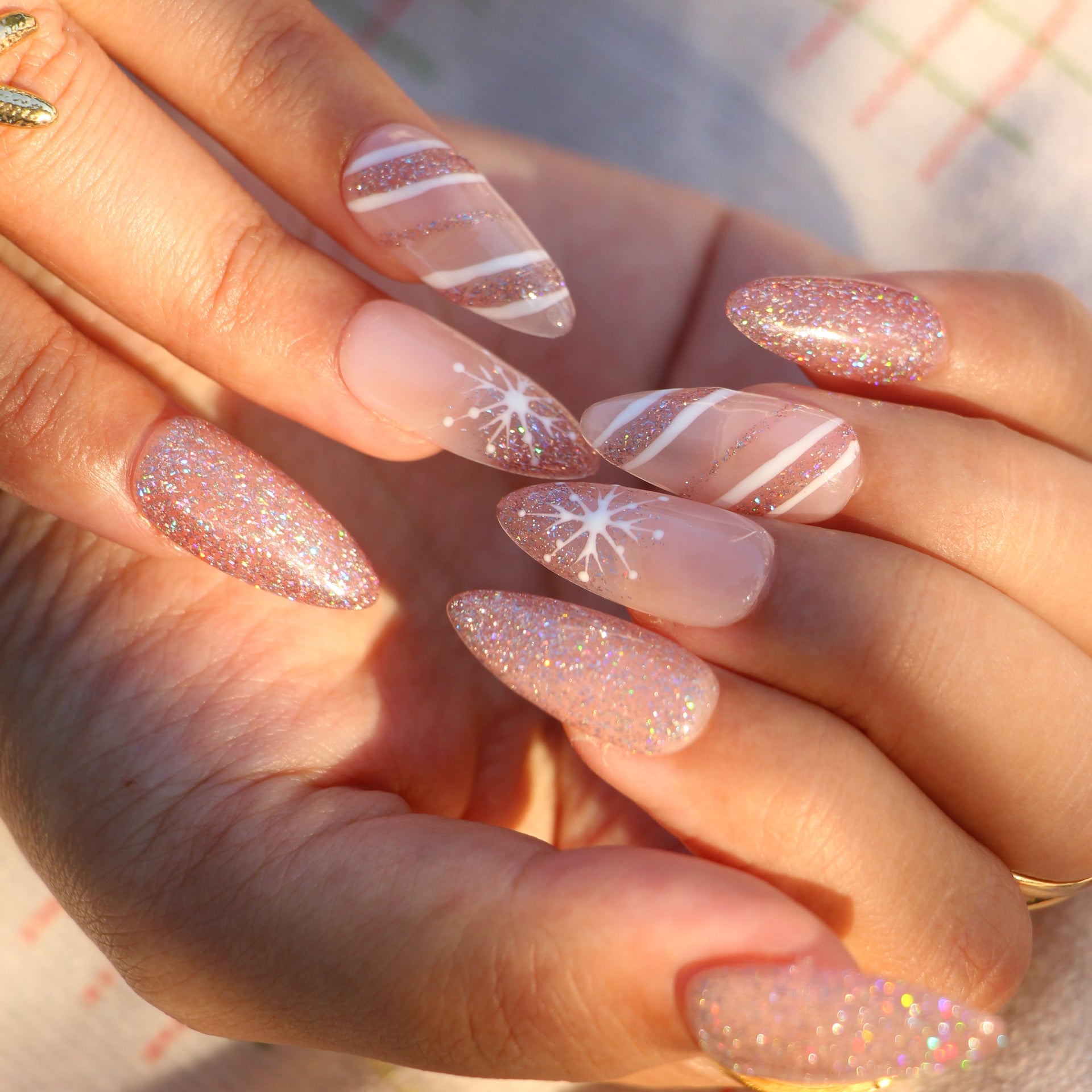 Rose gold holographic glitter nails with white snowflake nail art