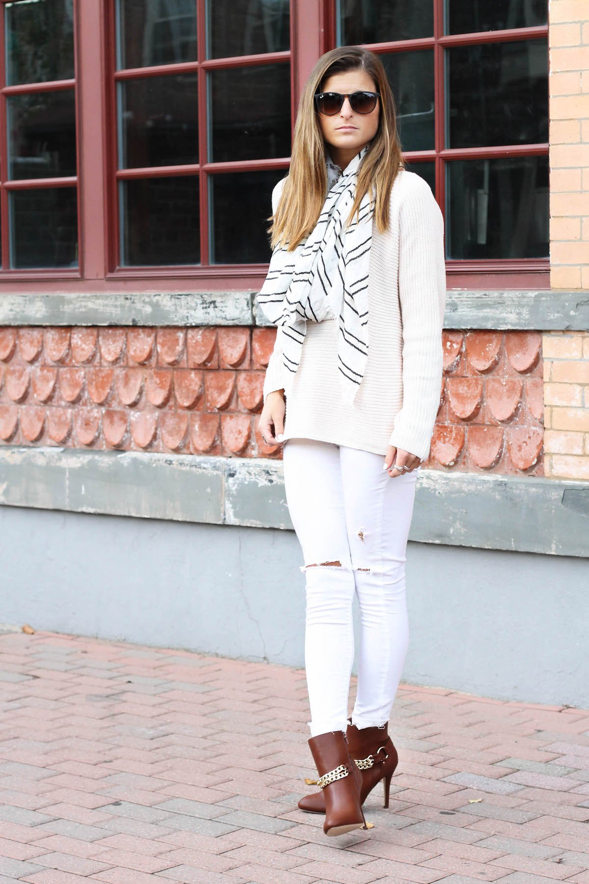 Cream oversized knit sweater with white ripped skinny jeans, brown heeled booties and a striped scarf
