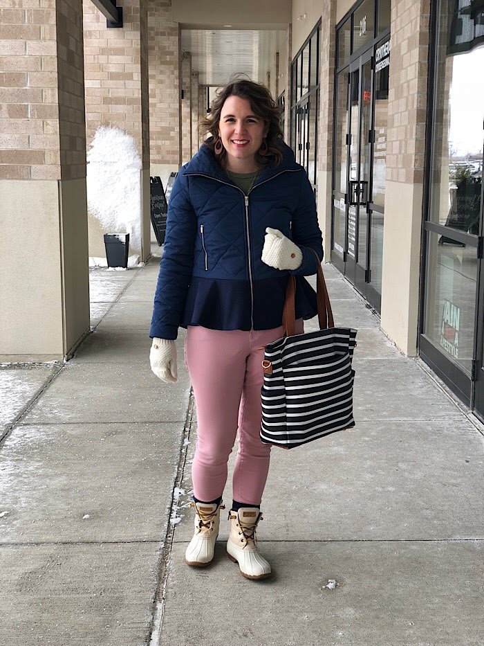 Woman in a navy quilted peplum jacket and pink jeans with cream duck boots