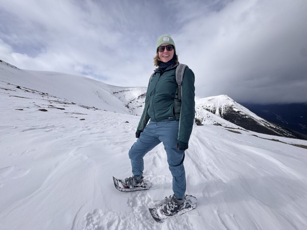 Woman in warm winter layers sightseeing on a snowy trail in Banff