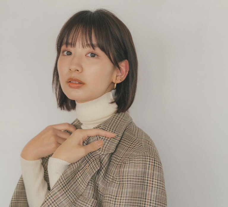 Woman wearing a white turtleneck under a checked plaid coat