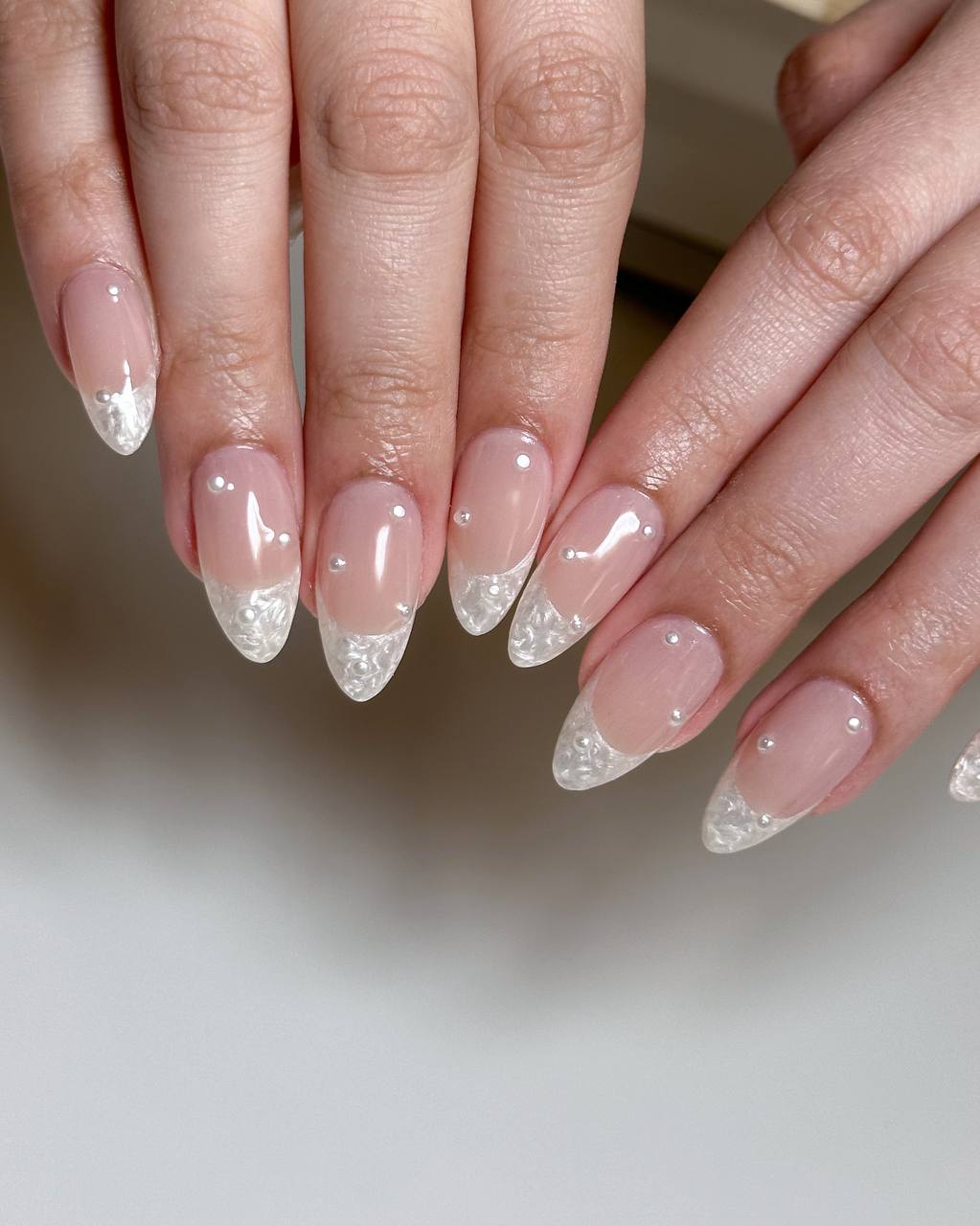 Frosted pearl French tips with pearl studs on nude nails