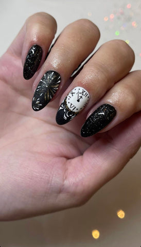 Black glitter almond nails with gold firework burst art and a white clock-face accent nail