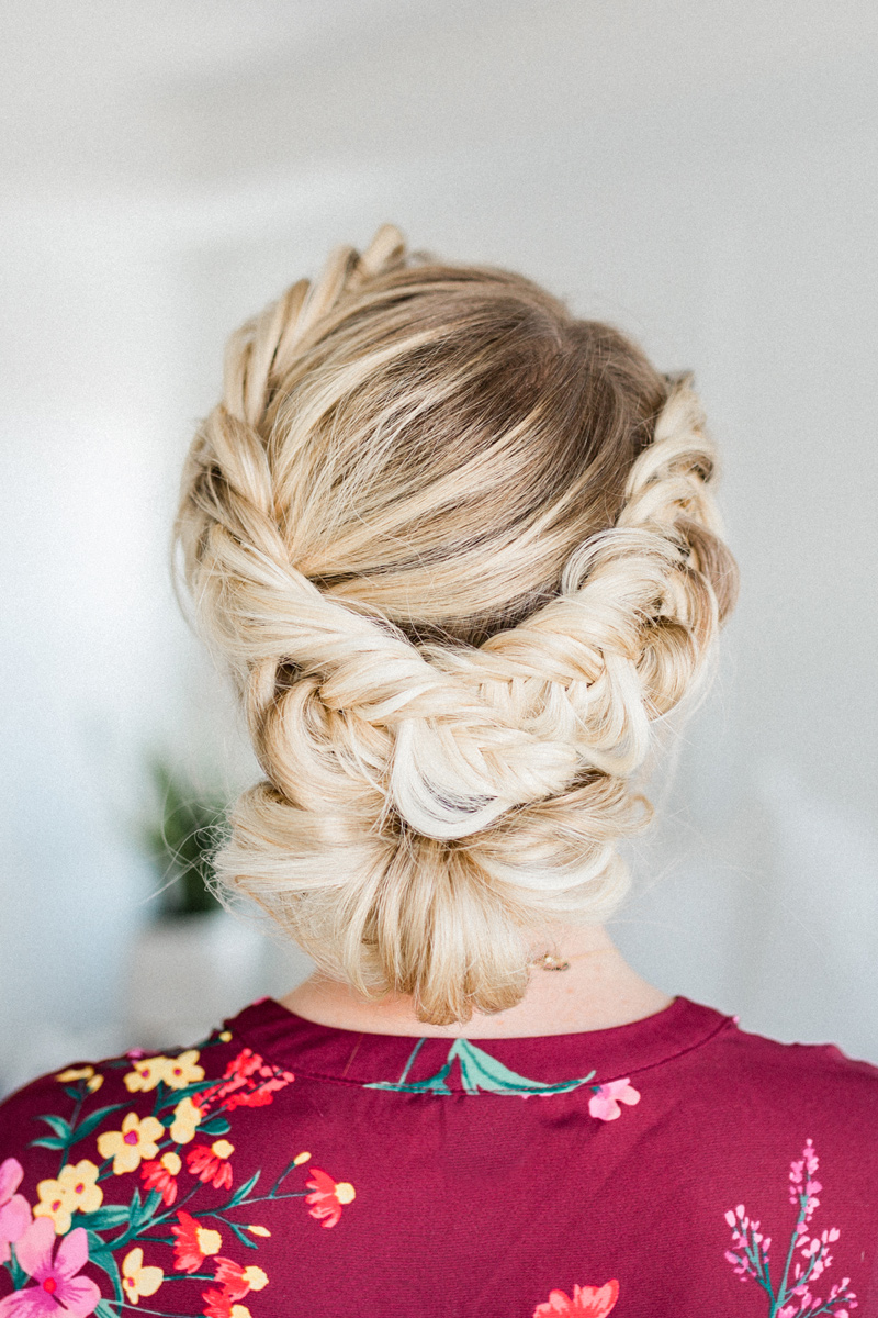 Fishtail braids wrapped into a low updo on blonde hair
