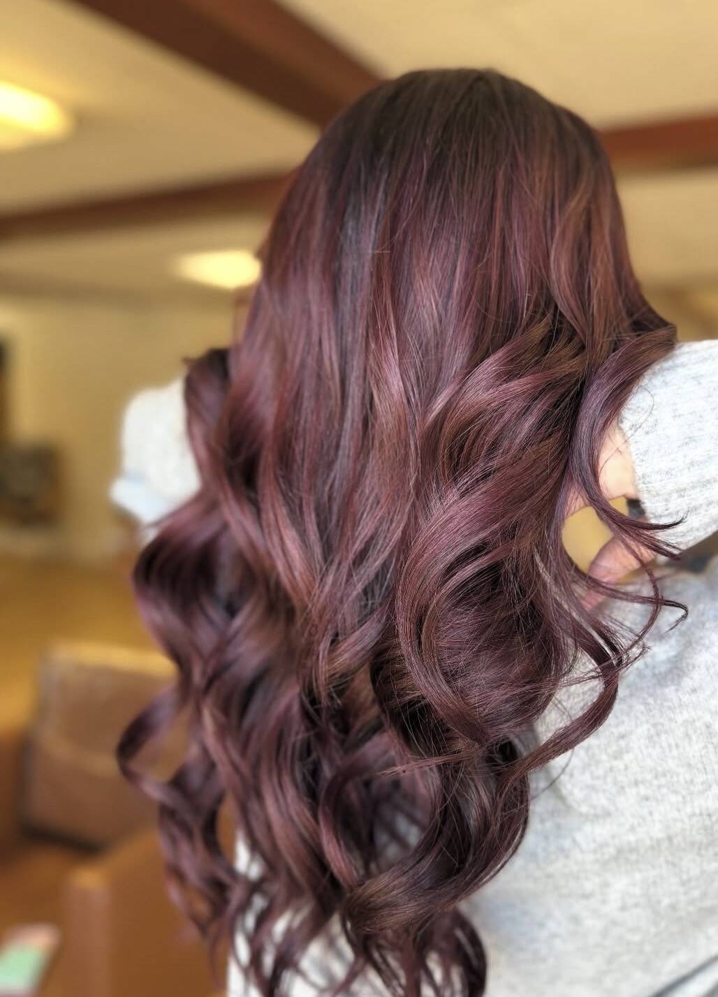 Deep burgundy plum hair color in long glossy waves
