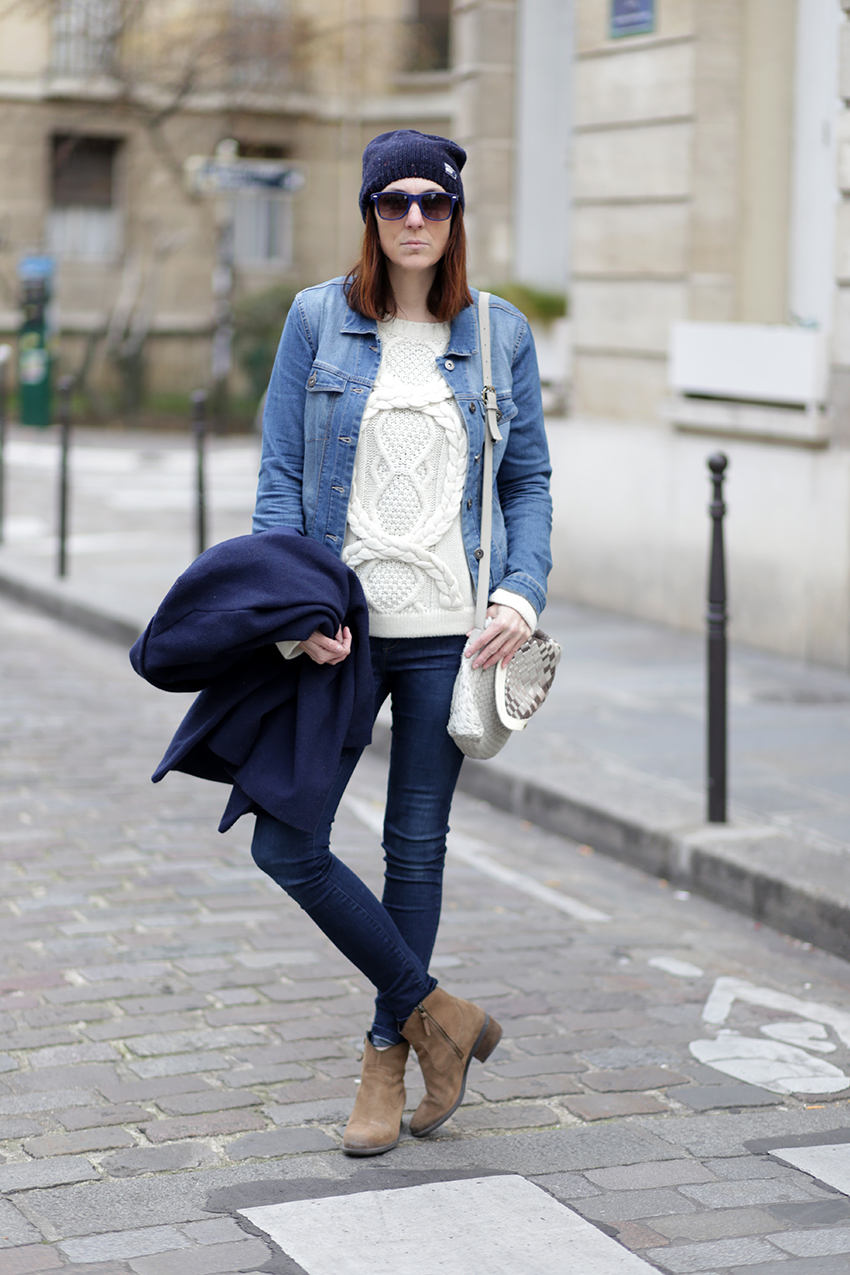 Woman in a navy beanie, denim jacket, cable knit sweater and suede booties