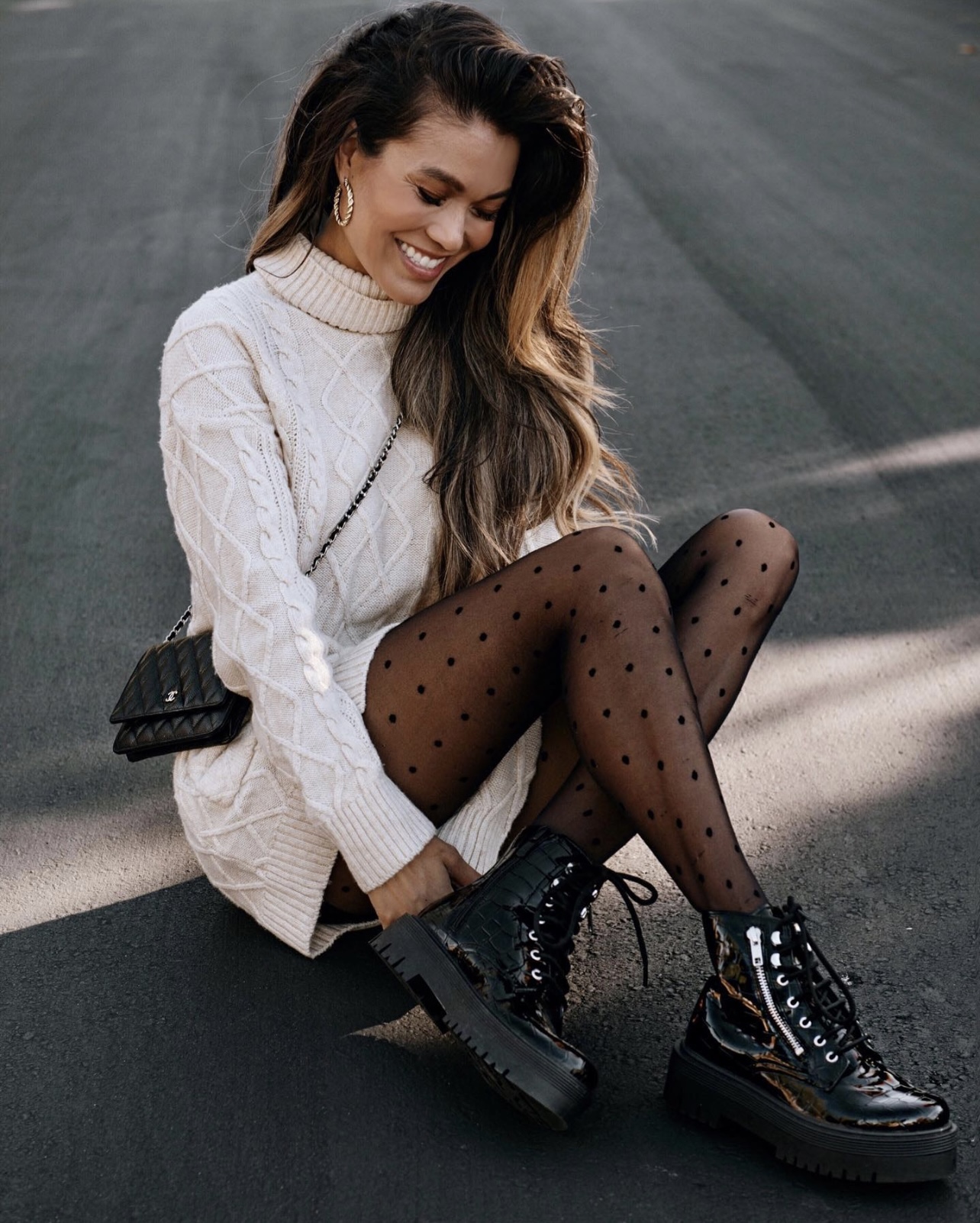 Cream cable-knit turtleneck sweater dress with sheer black polka-dot tights, chunky black lace-up combat boots and a black quilted chain-strap bag