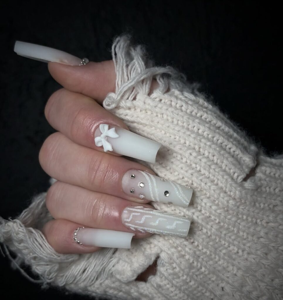 Long white coffin nails with a 3D bow, rhinestones, wavy white line art and cuticle glitter