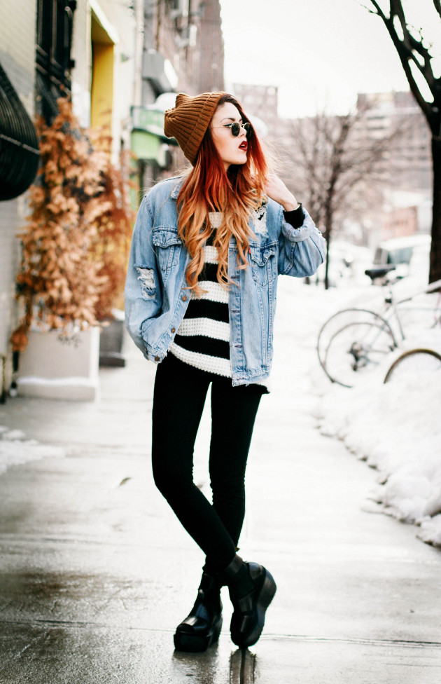 Woman in a tan beanie, denim jacket, striped sweater and platform boots in the snow