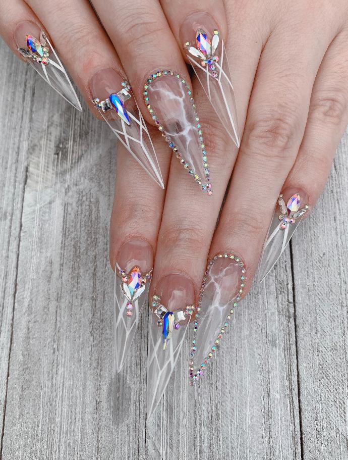 Very long clear stiletto nails with embedded crystals and fine white line art
