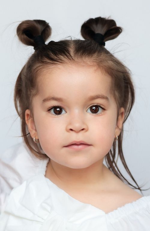 Toddler with two high space buns and loose hair