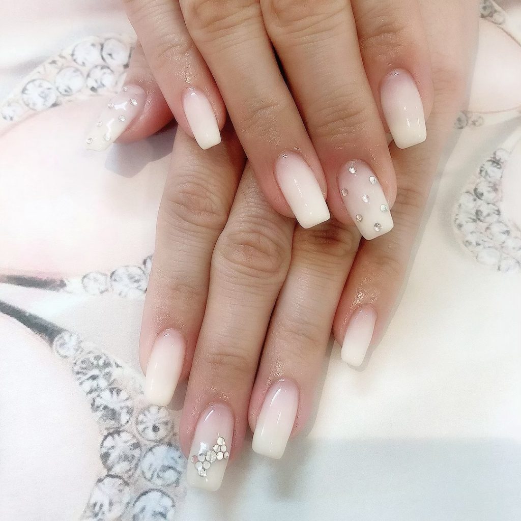 Milky white gradient nails with crystal clusters on accent nails