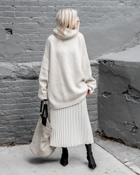 Woman wearing a chunky knit sweater with a pleated midi skirt