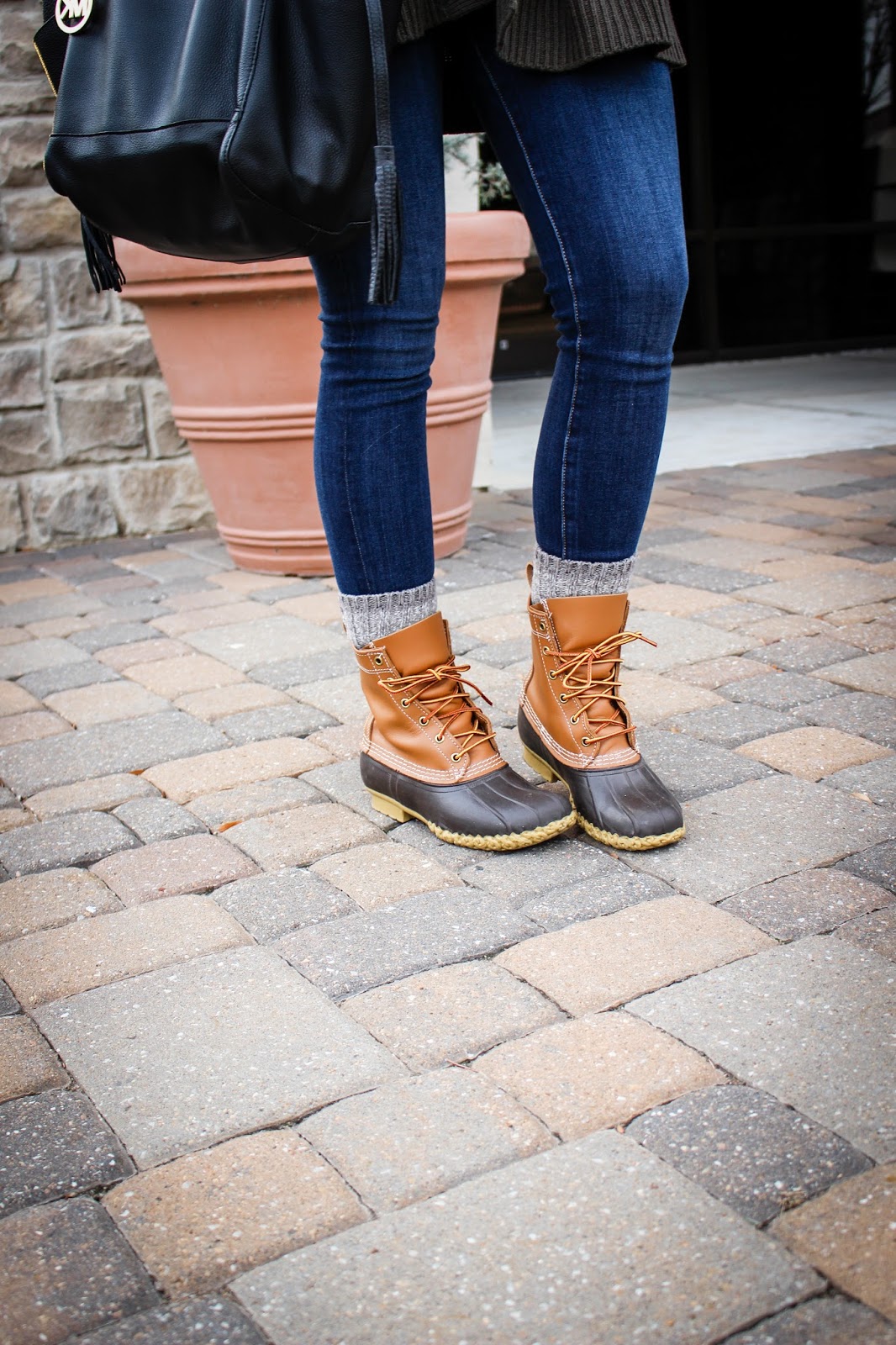 Close-up of tan and brown duck boots with blue jeans and grey knit socks