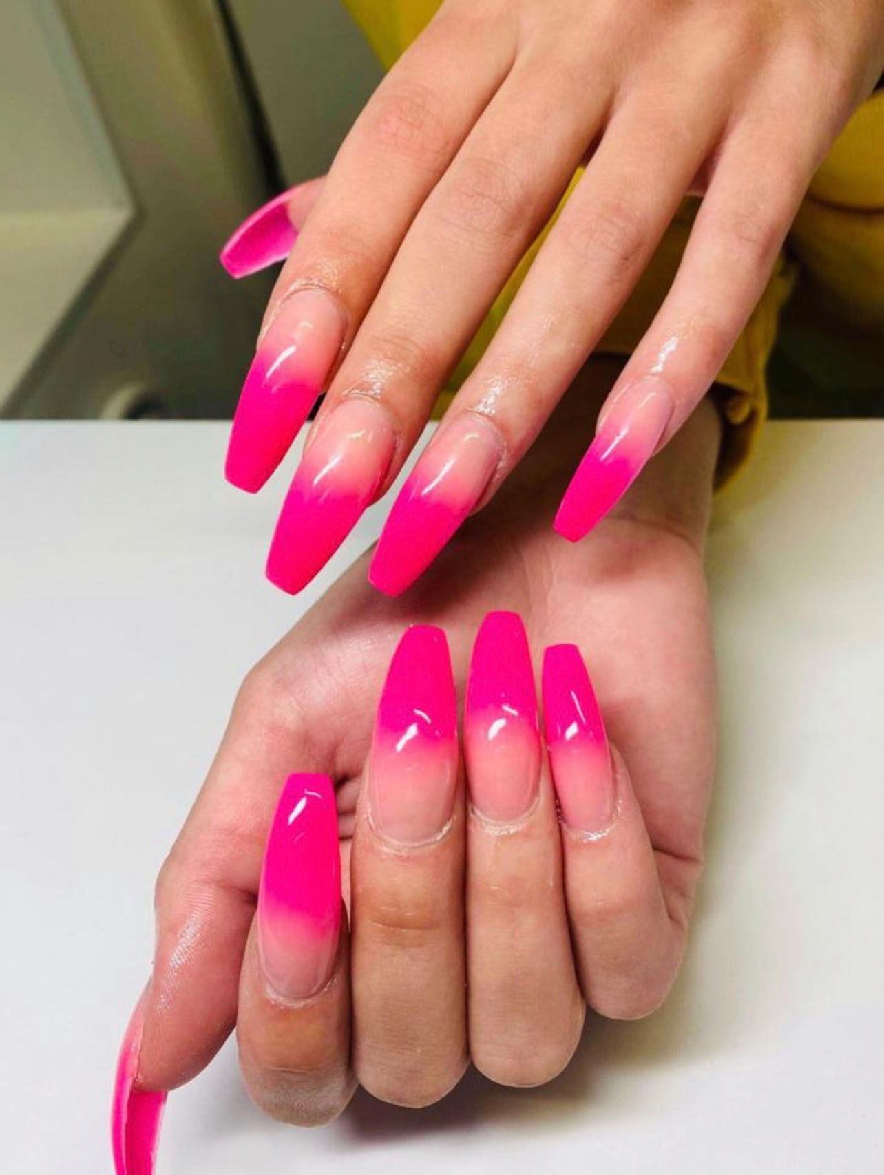 Long coffin nails fading from soft rose pink to vivid magenta tips with a glossy finish