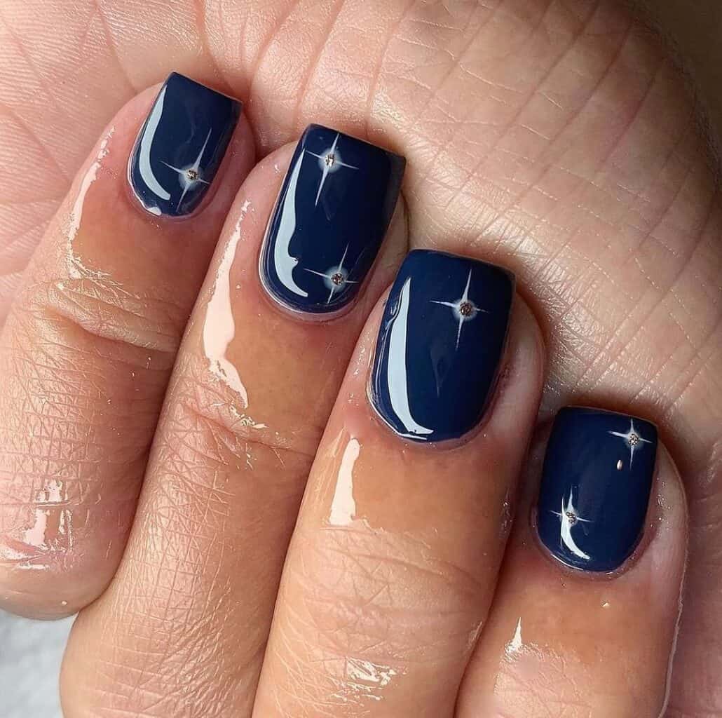 Short navy nails with white starburst lines and a tiny rhinestone at the center of each burst