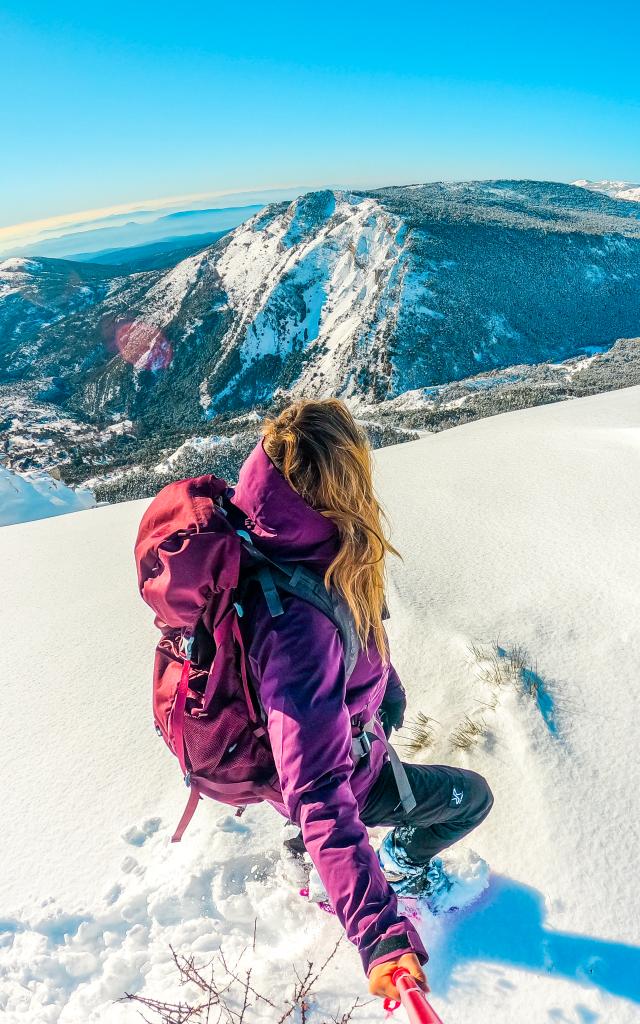 Woman snowshoeing in bright winter gear in the French Alps