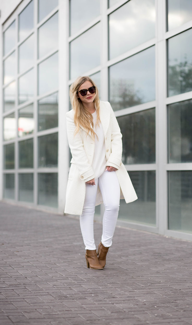 Fashion blogger in a winter-white look: ivory double-breasted peacoat, white knit top, white skinny jeans and tan ankle boots