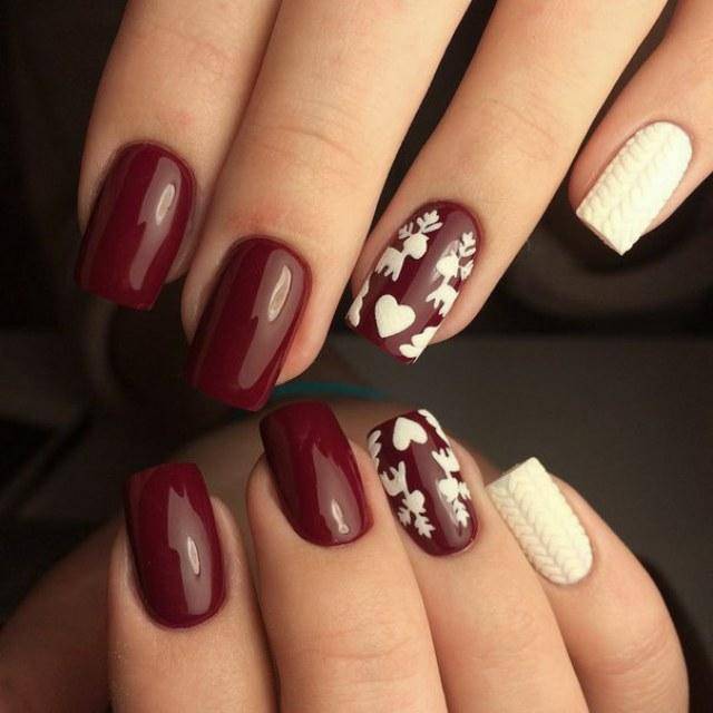 Glossy burgundy nails with white cable-knit sweater texture and floral accent nails