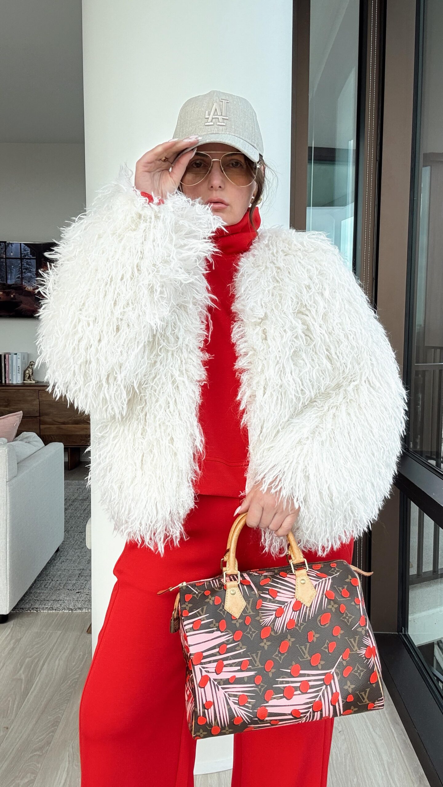 Woman in white shaggy faux fur coat over red knit with designer bag