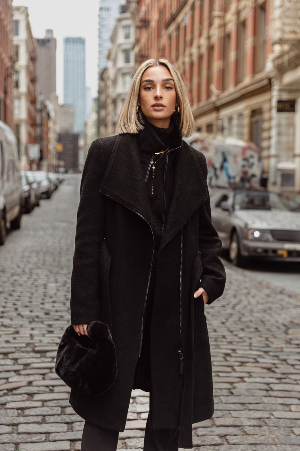 Woman in an all-black outfit with a black wool coat