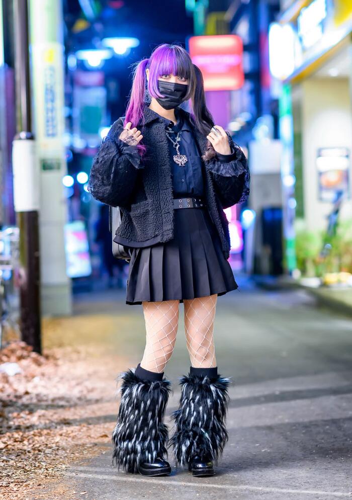 Black and grey furry leg warmers with fishnet tights, pleated black mini skirt and platform boots in a night street style