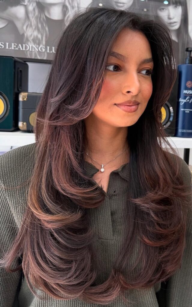 Long brunette hair with chestnut balayage, soft layers and a long curtain fringe, styled in a salon