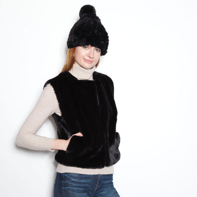 Black faux fur vest over a cream turtleneck with blue jeans