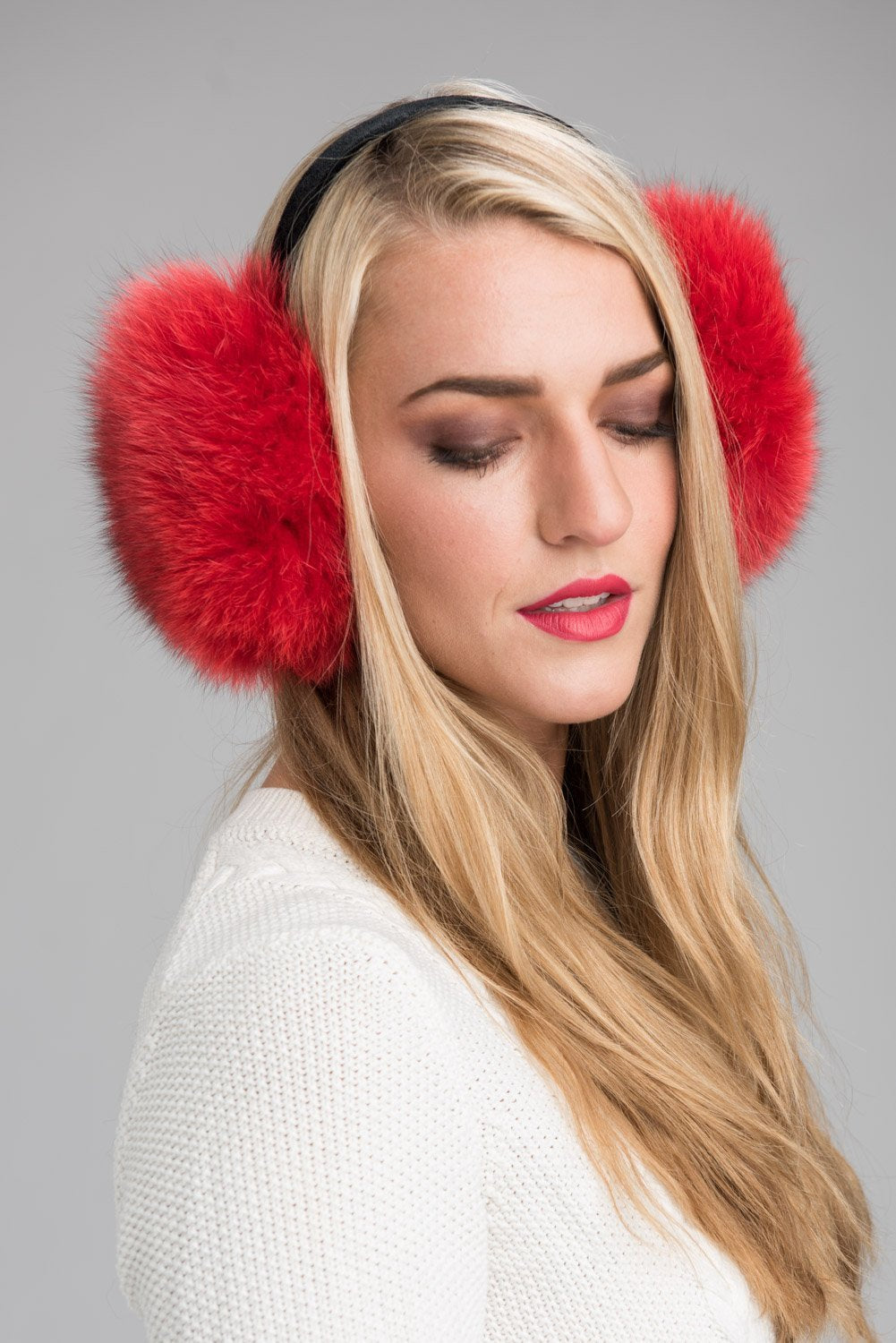 Woman in red fox fur earmuffs and a white knit sweater