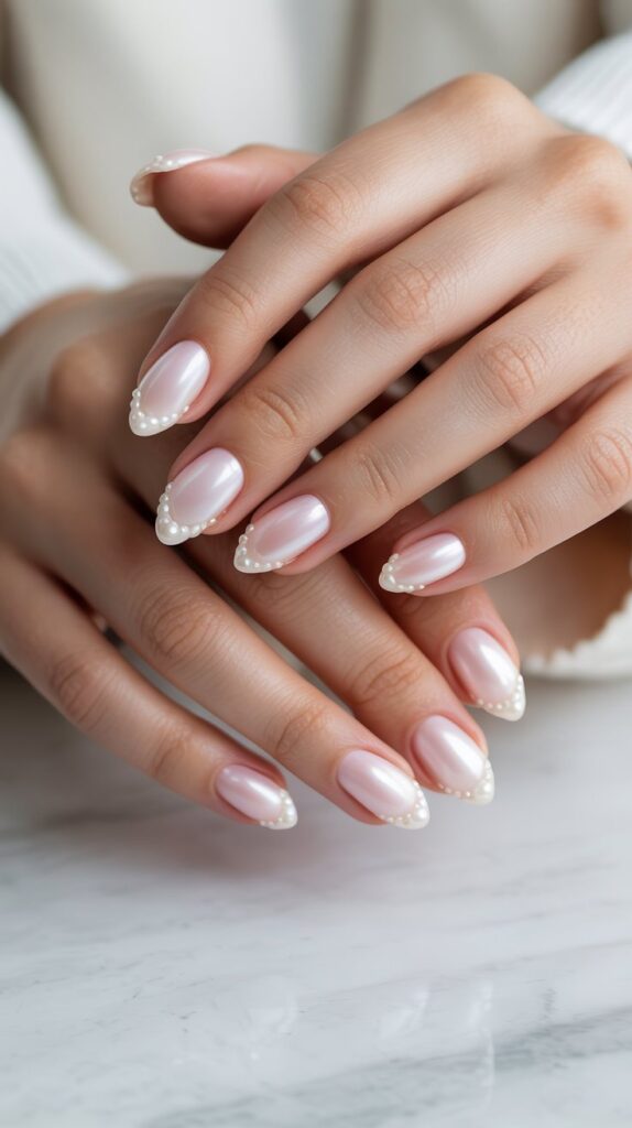 Milky pink nails decorated with small pearl accents