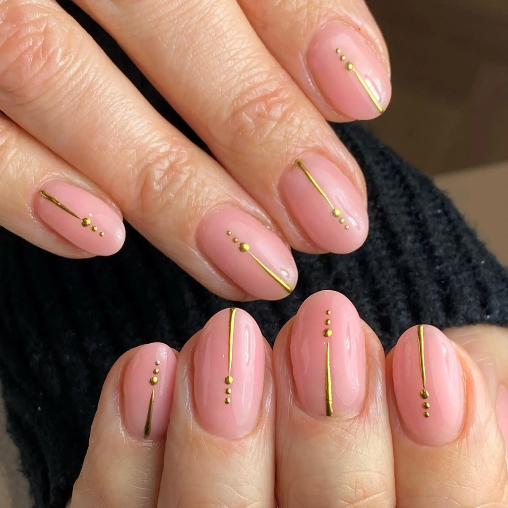 Short oval soft pink nails with gold line and dot accents